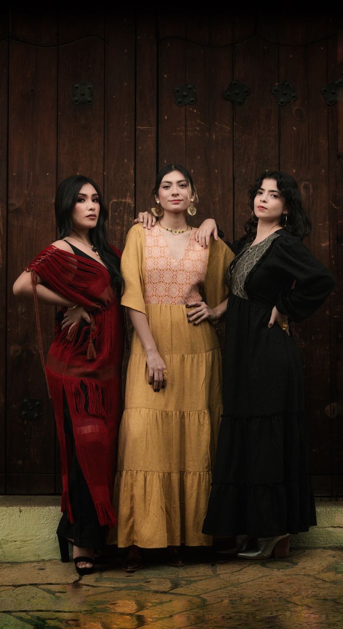 Three women in traditional dresses pose in San Cristóbal de las Casas, México.
