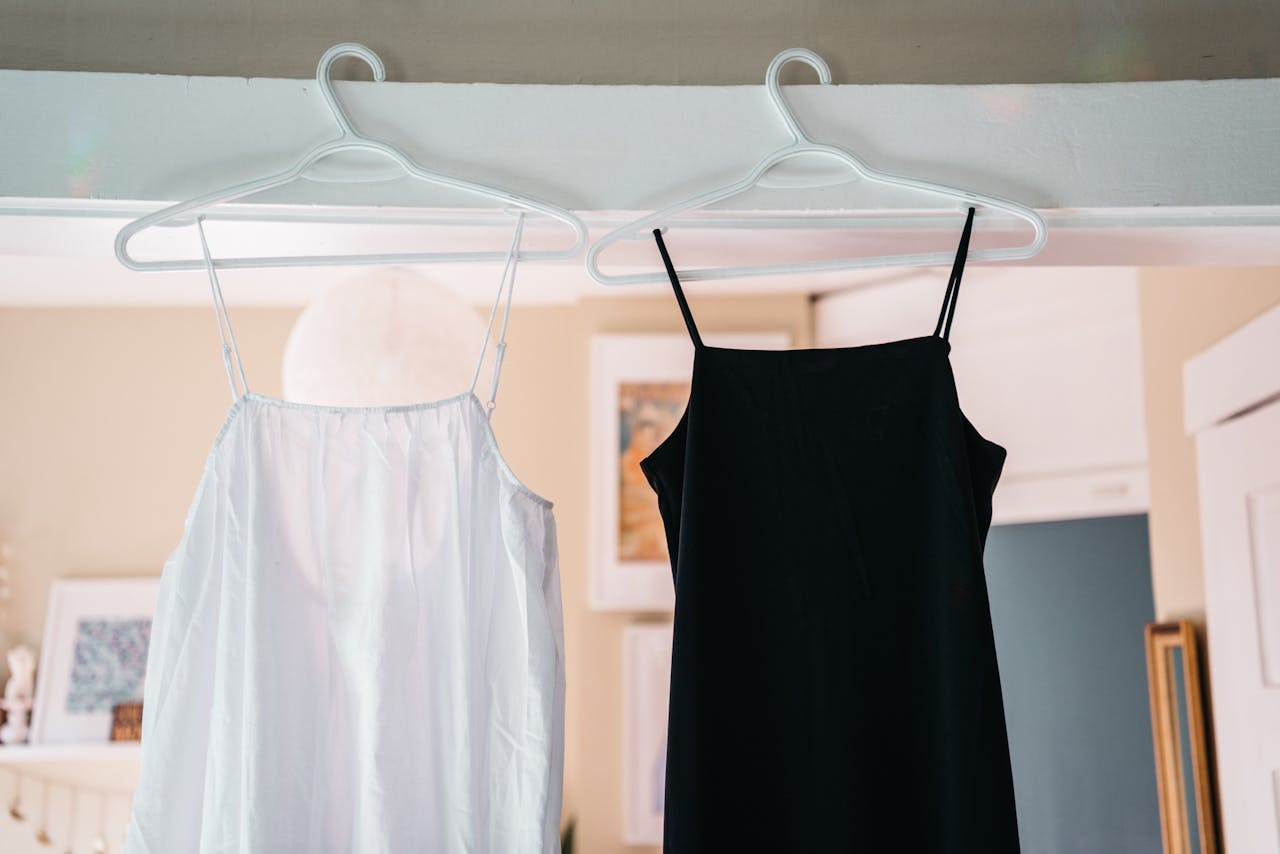 Minimalist display of black and white spaghetti strap dresses hanging indoors.
